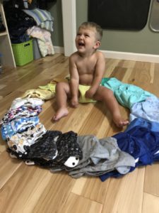 Toddler in cloth diaper surrounded by a ring of assorted cloth diapers
