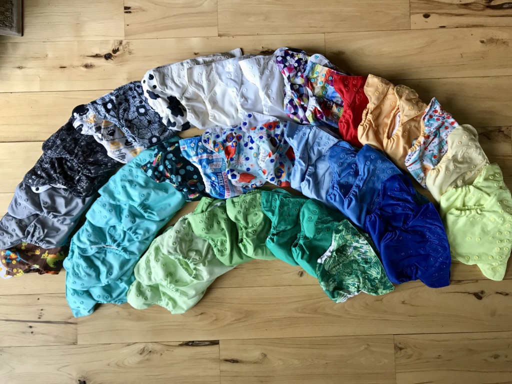 Set of one-size, all-in-one cloth diapers arranged in a rainbow pattern