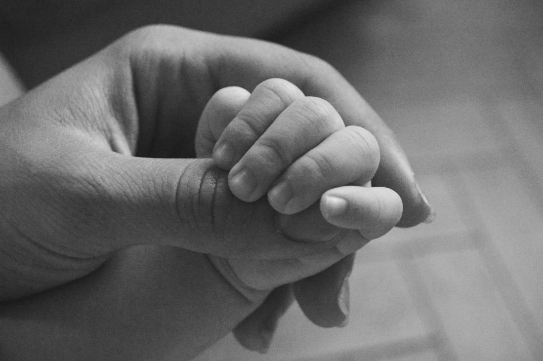 Black and white photo of baby's hand in mother's
