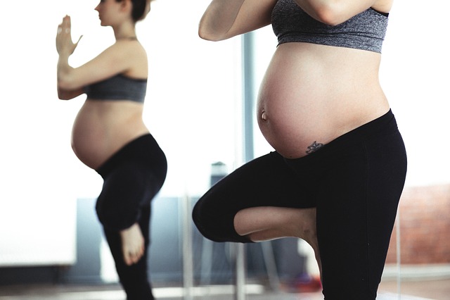 Pregnant woman doing tree pose in yoga - photo taken from side view into mirror